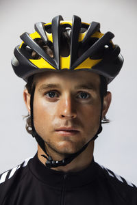 Portrait of confident cyclist wearing helmet against white background