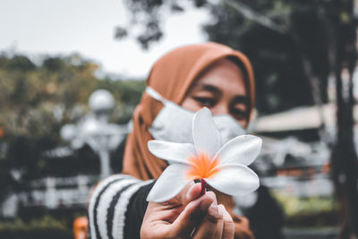 Close-up portrait of woman holding flowering plant