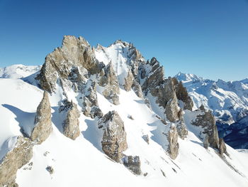 Scenic view of snow covered mountains against clear blue sky