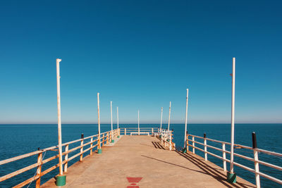 Pier over sea against clear blue sky