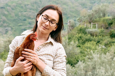 Woman holding brown hen in her hands in the farm. free-grazing domestic hen on organic farm.