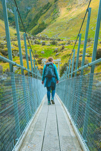 Rear view of woman walking on footbridge