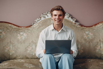 Portrait of young woman using laptop while sitting on sofa at home