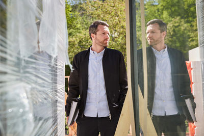 Businessman with file reflecting on glass at construction site