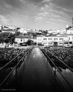 Bridge over river amidst buildings in city against sky