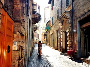 Rear view of woman walking on street amidst buildings in city