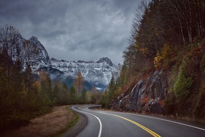 Road by trees and mountains against sky