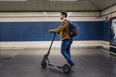 Side view of man with umbrella walking on tiled floor