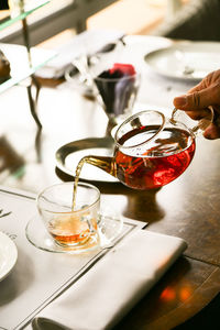 Cropped hand of person pouring tea in cup from pot