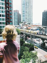 Rear view of woman standing against buildings in city