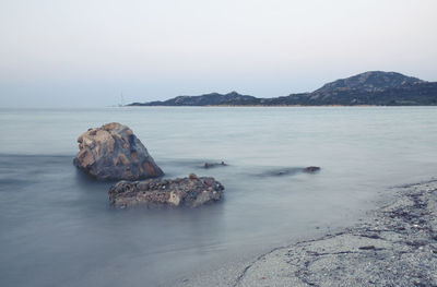 Rock formation in sea against clear sky