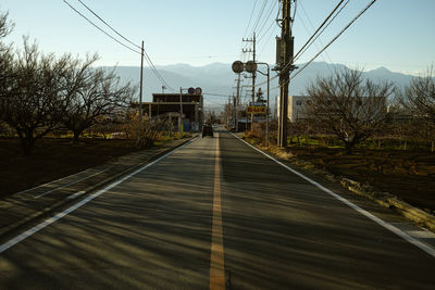 Road by trees against sky