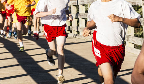 Boys racing a high school cross country race going over a wood bridge at sunken meadow state park.