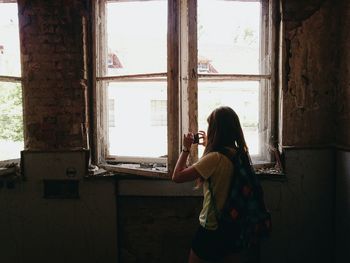 Woman photographing through window in abandoned house