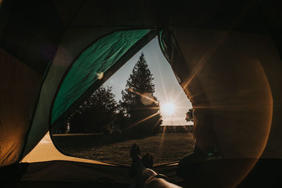 Low section of person in tent against sky during sunset
