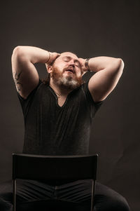 Midsection of man sitting on chair against black background