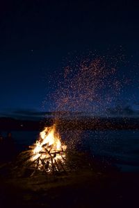 Bonfire on beach against sky at night