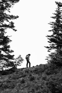 Low angle view of man standing by tree against clear sky