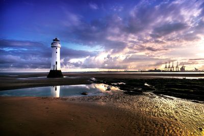 Lighthouse by sea against sky