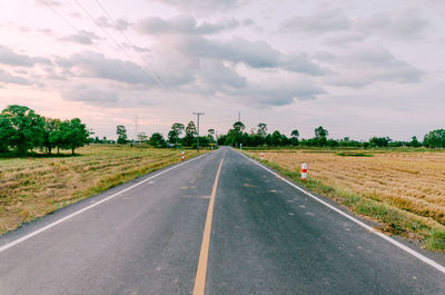 Road amidst field against sky