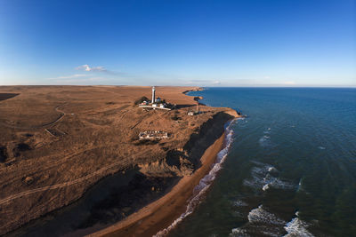 Aerial view of the lonely lighthouse standing on the edge of the cliff. at the edge of the sea