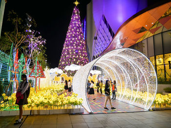 People walking on illuminated street at night