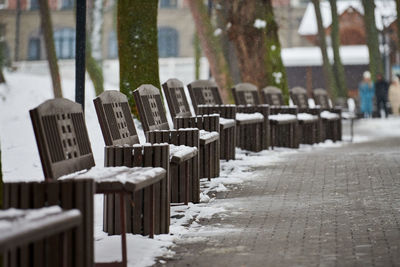 Benches covered with snow among frosty winter trees in park. winter landscape, falling snowflakes