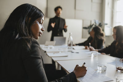 Female entrepreneur taking down notes during business meeting at office