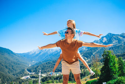 Full length of woman with arms outstretched against mountain range