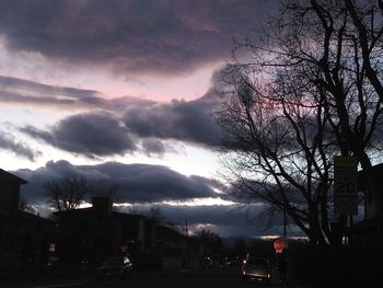 Silhouette of city against cloudy sky at night