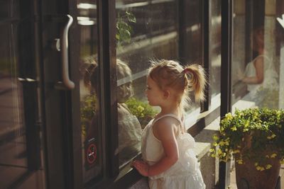 Side view of girl looking through window