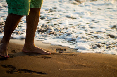 Low section of man standing on beach