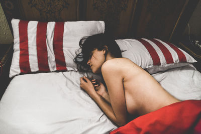 Sensuous shirtless woman sleeping on bed at home