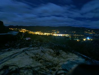 Illuminated cityscape by sea against sky at night