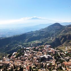 Aerial view of town by mountains against sky