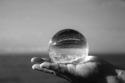 Close-up of hand holding water against sky