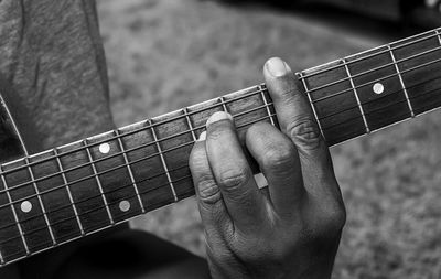 Cropped hand playing guitar outdoors