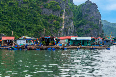 Boats in river by trees against mountains