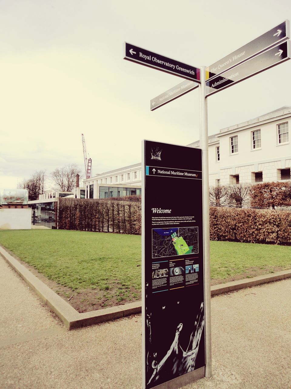 architecture, building exterior, built structure, communication, text, western script, grass, sky, city, green color, day, sign, road, outdoors, building, street, information, no people, road sign, tree