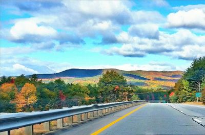 Road passing through landscape against cloudy sky