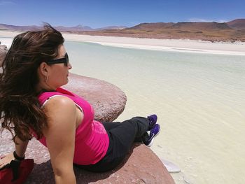 Full length of woman relaxing on rock at lake