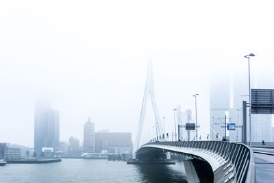 Bridge over river in city against clear sky