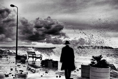 People on beach against cloudy sky