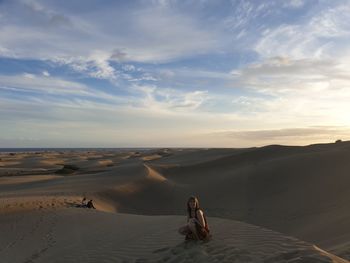 People sitting on beach against sky during sunset