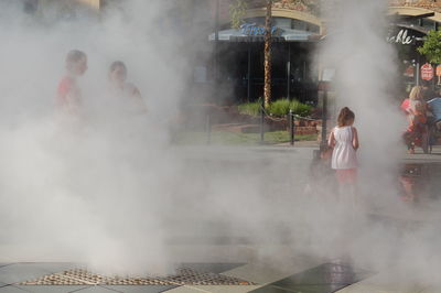 People standing in smoke on footpath