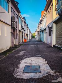 Empty road amidst buildings in city