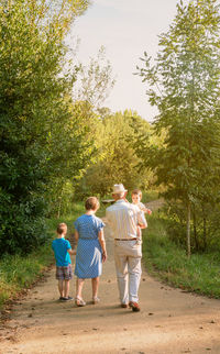 Rear view of family walking on footpath amidst plants