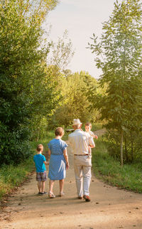Rear view of people walking by plants