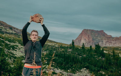 Portrait of young woman standing against mountain