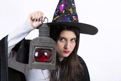 Young woman in spooky costume holding red light against white background